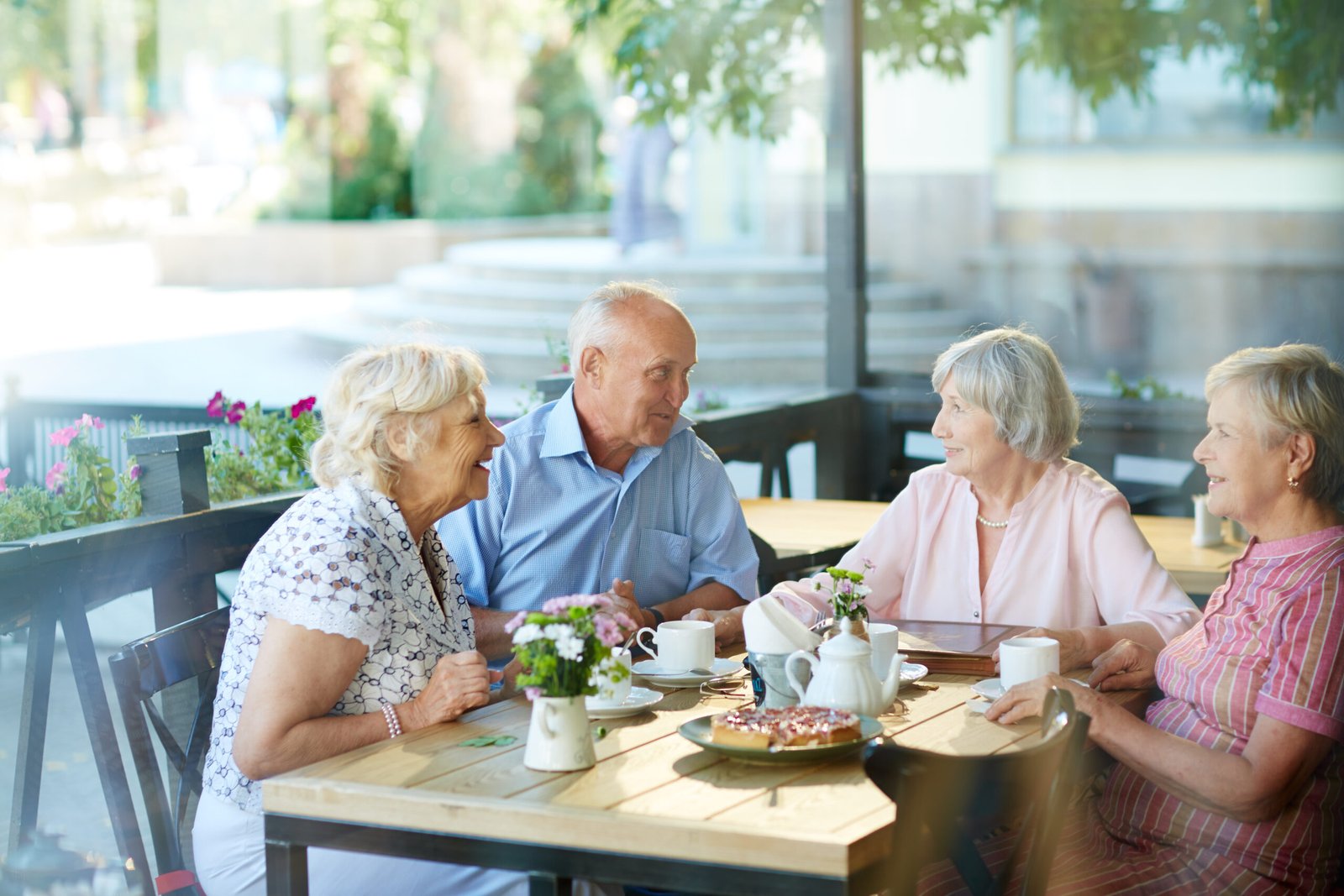 Four childhood friends gathered together in outdoor cafe after long separation and remembering funny stories from their past